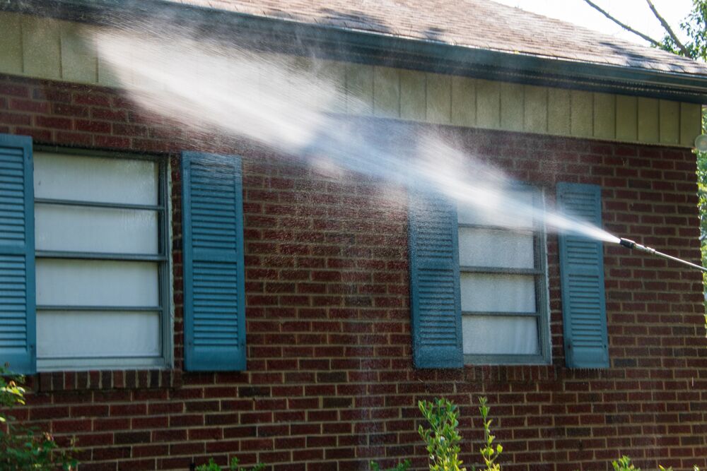 worker performing soft washing services on a commercial building